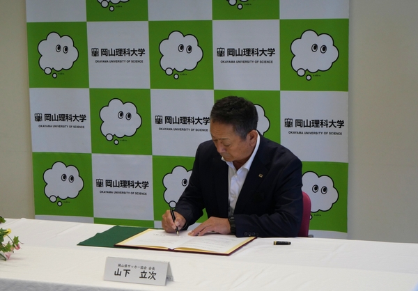 協定書に署名する山下会長