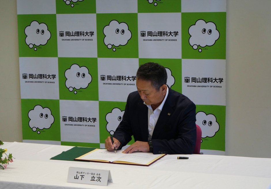 協定書に署名する山下会長