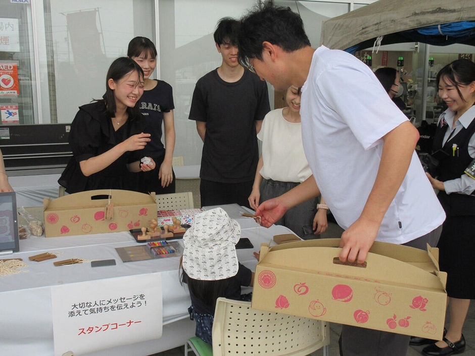 新パッケージで「しのおかの桃」を販売する学生たち