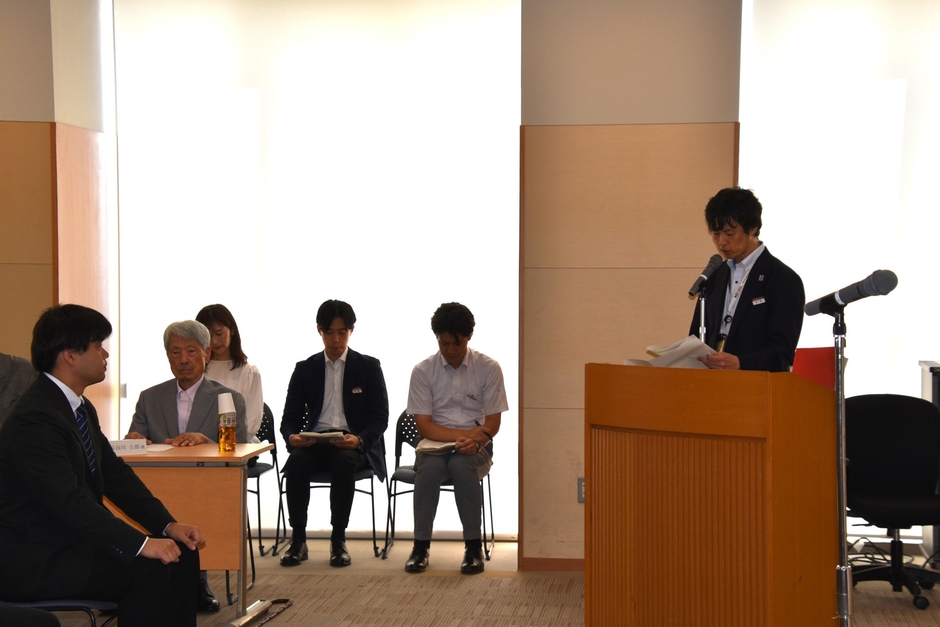 大竹課長(右)が長谷川顧問のあいさつを代読