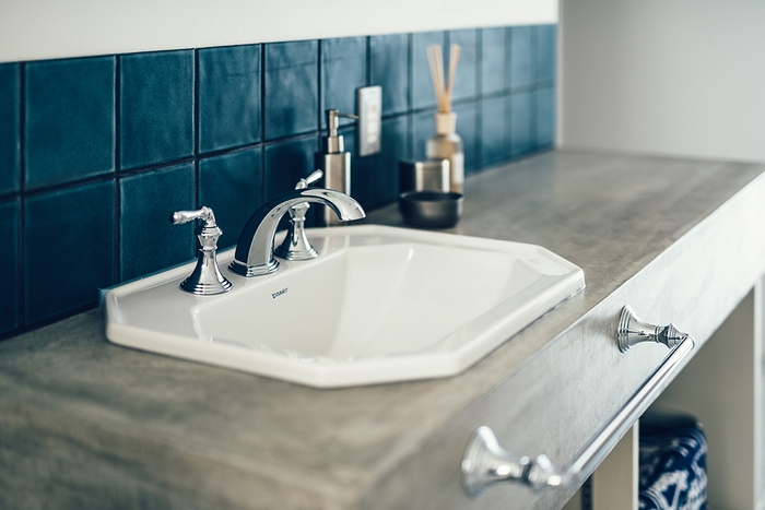 間口の狭い空間を有効利用するため廊下に設けたモルタル仕上げの洗面台。