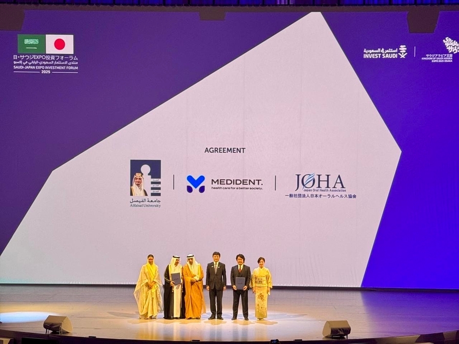 会場スクリーンに表示された提携3者のロゴ(Alfaisal University/MEDiDENT/日本オーラルヘルス協会)。公式プログラムとして壇上で合意。