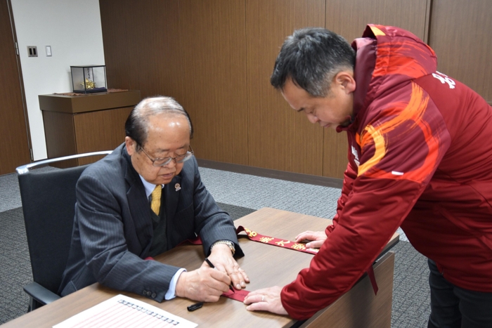 たすきに激励のメッセージを書く立花理事長