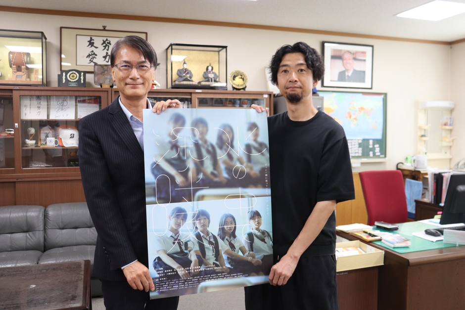 附属高の近藤校長（左）と映画のポスターを掲げる安井さん（右）