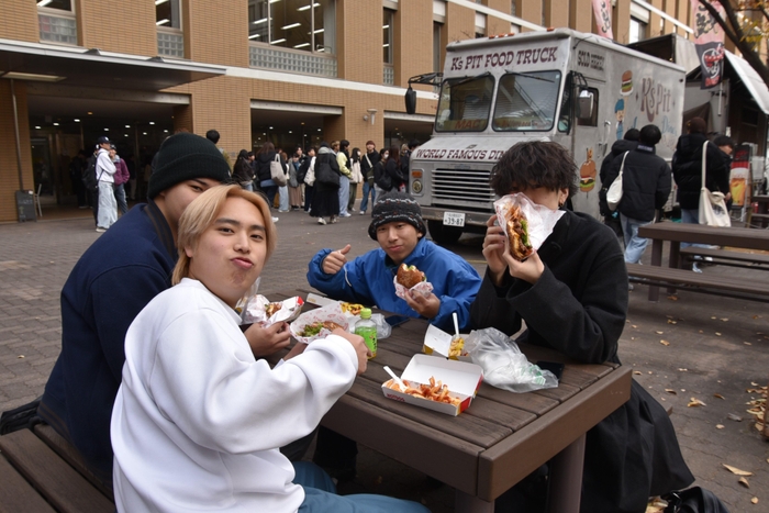 キッチンカーで購入したハンバーガーを味わう学生たち