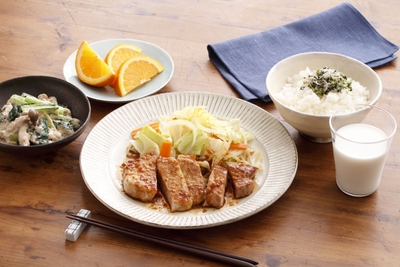 【肉が主役の晩ごはん】厚切り豚のしょうが焼き（★）、小松菜としめじの白あえ、ご飯、牛乳、オレンジ。ボリューム感のあるとんカツ用の豚肉でしっかりたんぱく質をとります。豚肉は糖質をエネルギーに変えるためのビタミンB1が豊富！　添える野菜には、ビタミンB1の吸収を高めるアリシンを含む玉ねぎを加えます。