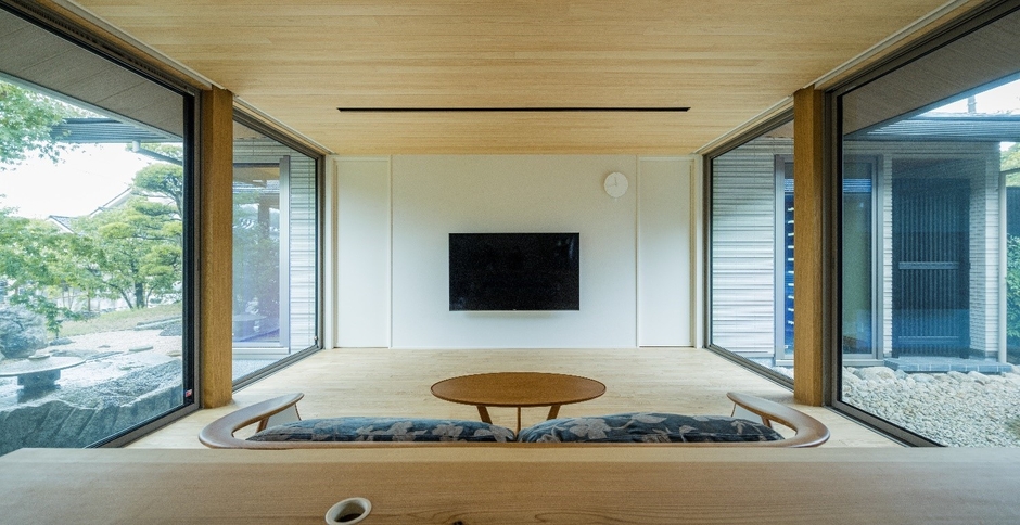 小上がりの畳コーナーから南北の庭に囲まれたリビングを望む