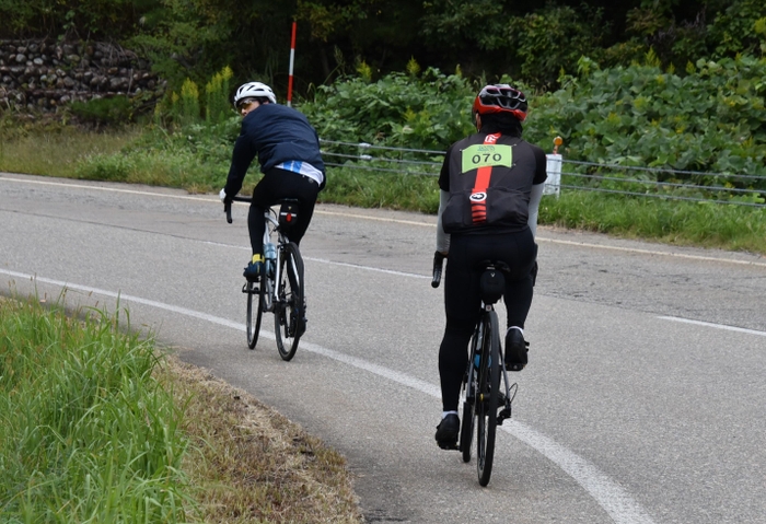 並走しながら選手（右）を見守るサイクリング同好会の学生