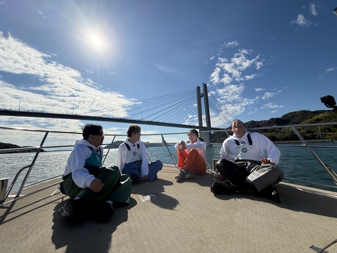 瀬戸内海を船で移動する4人（左から伊藤、村上、本田、関口）