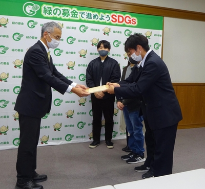 寄付金と目録を手渡す