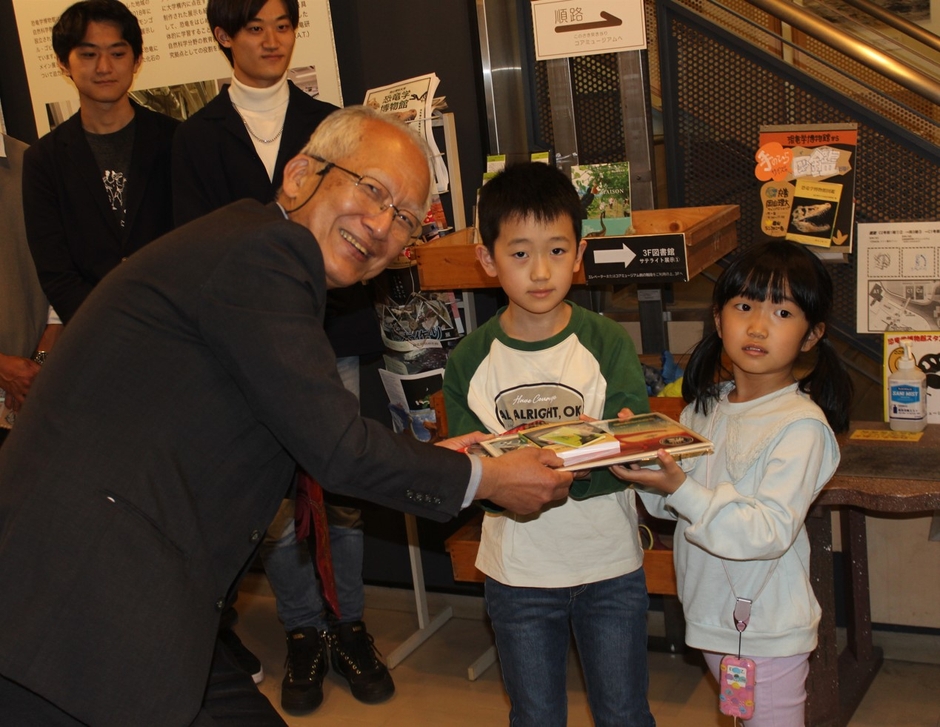 石垣館長から記念品を受け取る末富君(中央)。右は妹の栞ちゃん