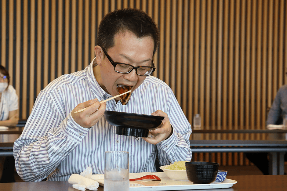 おいしそうにウナギを頬張る男性教員