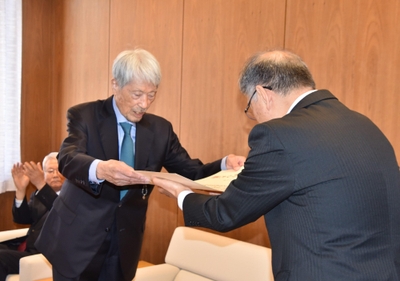 野口学長（右）から名誉学位記を手渡される長谷川顧問