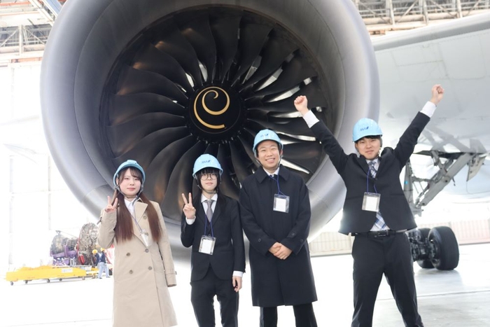 エンジンの前でポーズを取る学生たち