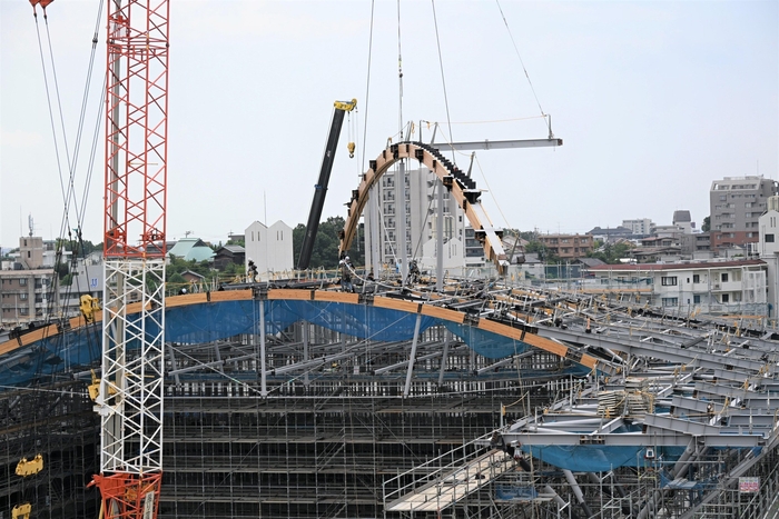 アーチ状の梁が大型クレーンで吊り下げられる様子