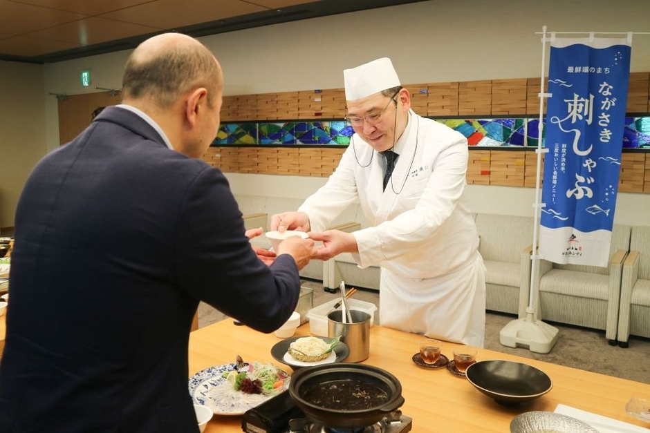 「夏限定 ながさき刺しゃぶ完成報告会」にて、 鈴木史朗長崎市長(左)へ新メニューを紹介する様子