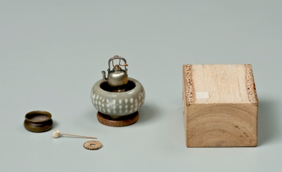Photo.03 お茶道具のミニチュア 火鉢(1.54×2.24)、薬缶(1.40×0.81)、建水(0.50×1.21)、瓶敷(1.78×0.75)、茶杓(1.78) ※サイズの単位:cm 火鉢と薬缶は中田實の掌に載せられたもの