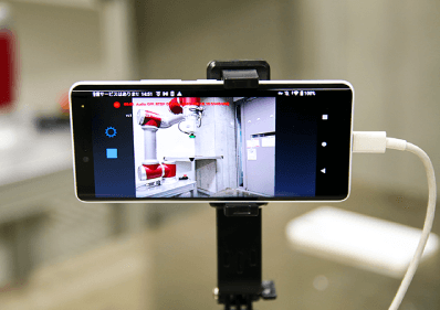 遠隔操作のカギになるカメラはスマホで代用が可能。協働ロボットは複雑な動作を数多く覚えられるため、パーツやプログラムの差し替えによって、工場内を移動させて異なる種類の作業を支援させることも実現できる