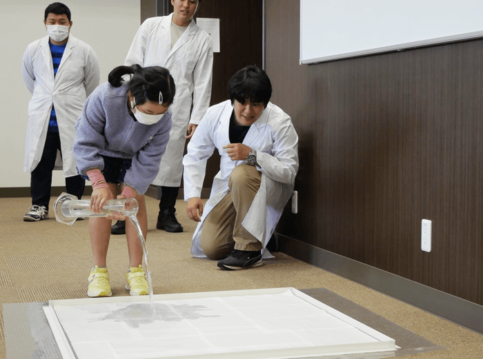 雨量１ミリメートルの水量を体験してみる小学生の参加者