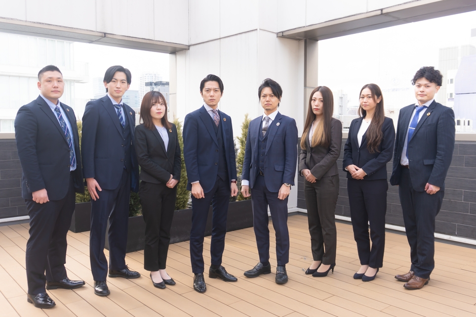 東京本社の屋上テラスでの集合写真。中央左の男性が販売部マネージャー・傳田。