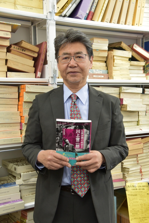 著作を手にする岩井教授