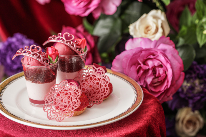 ▲スタンド上段スイーツ　イメージ　“プリンセスパフェ～薔薇香るルビーショコラ～”は、下からローズジュレ、ルビーショコラとラズベリーのムース、赤ワインジュレ、ラズベリーソルベの層になっているプティパフェ。“ラズベリーローズシュー”は、薔薇香る濃厚なベリーカスタードクリームが楽しめるシュークリーム。