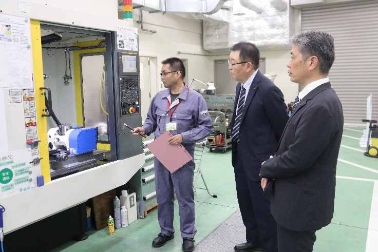 サイエンスドリームラボで寺野元規センター長（左）から機器の説明を受ける烏田社長ら