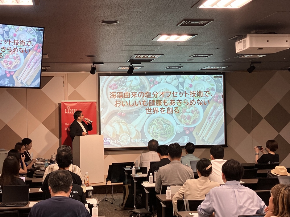 マイクを持つ代表取締役社長の竹下英徳