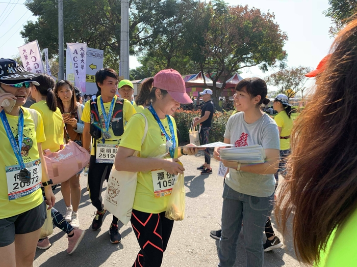 田中マラソン：ゴール地点でランナーに復興支援感謝を伝えるファイル配布しているシーンゴール地点でランナーに復興支援感謝を伝えるファイル配布しているシーン