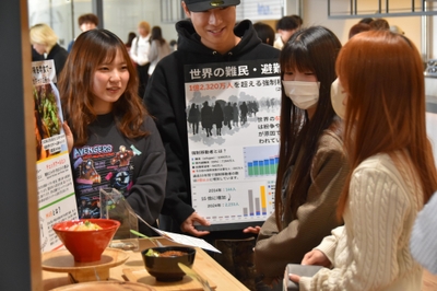 学生に「チェッタアールヒン」を勧めながら難民がおかれている現状を説明するゼミ生