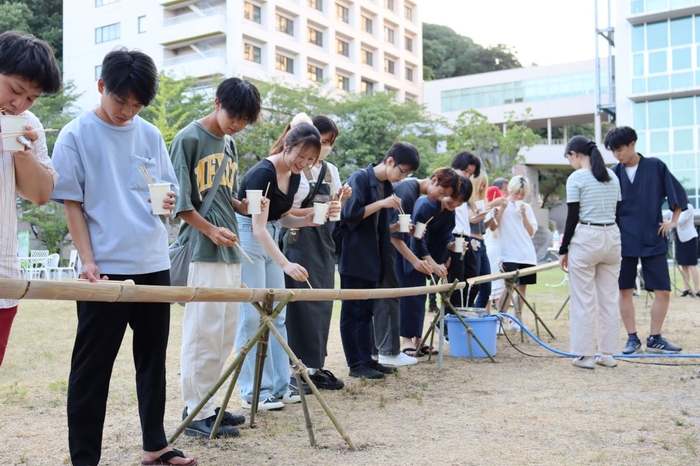 流れて来るそうめんを待ち構える学生たち