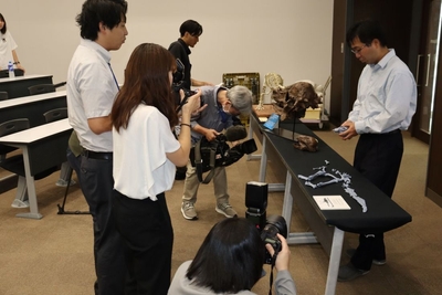 ザヴァケファレの実物大化石のレプリカを手に報道関係者に解説する高崎助教（右）
