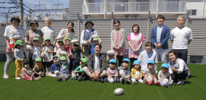 （保育園の園児たちに囲まれて写真撮影をする廣瀬氏＜中央＞）