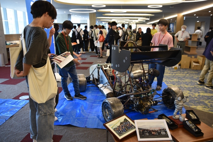 展示したフォーミュラカーを説明する理工学部の学生ら