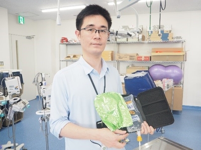 ポータブルタイプの点滴装置の試作機（3号機）を 手にする宮部助教