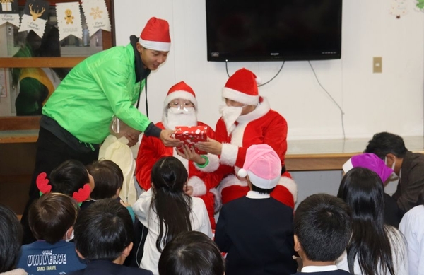 子どもたちにプレゼントを手渡す学生サンタさん