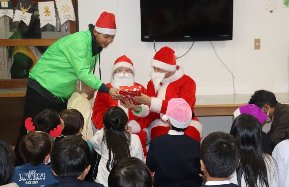 子どもたちにプレゼントを手渡す学生サンタさん