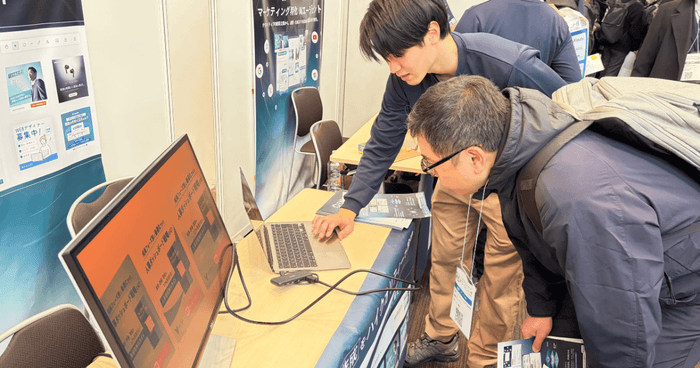 実際の画面を用いたデモンストレーションに真剣な表情で見入る来場者