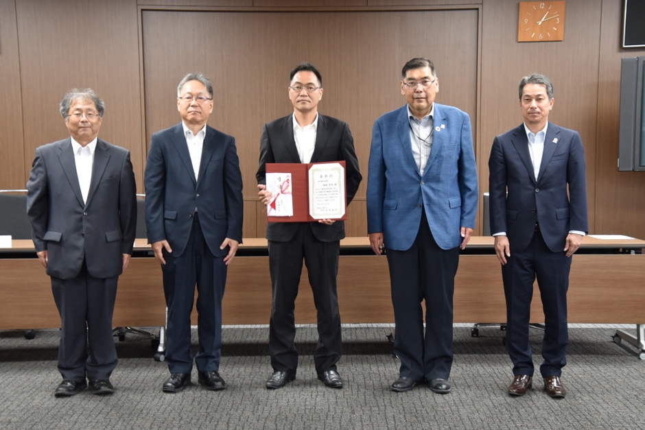 功労賞に選ばれた塚越教授(中央)を囲む小原学長ら