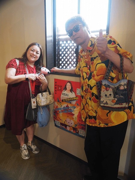 ポスターの前で写真を撮るSIZUKUとGOD