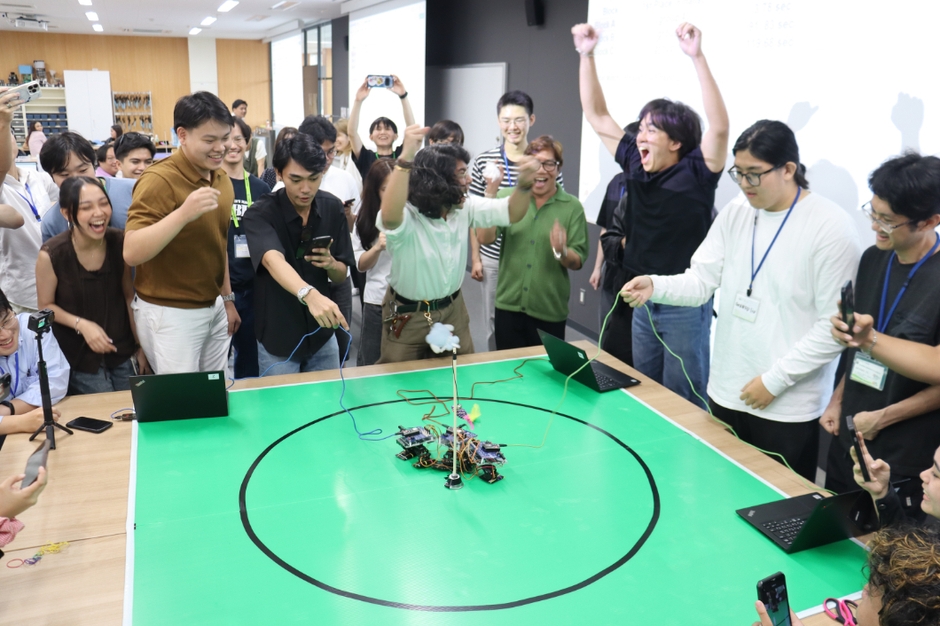ロボコンで優勝し、腕を突き上げて喜びを表現する学生たち