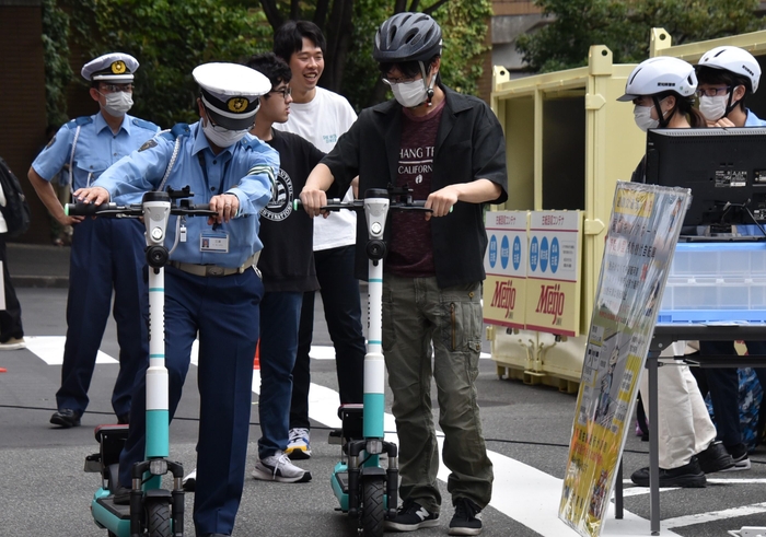 天白署員から電動キックボードの乗り方を教えてもらう学生