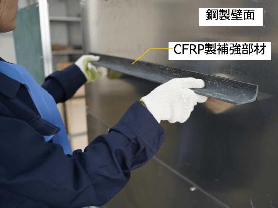 補強部材を壁面に接着している様子*（写真の試験体は本公開実験と異なります）