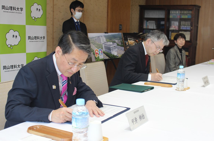 協定書に署名する平井知事（左）と平野学長（右）
