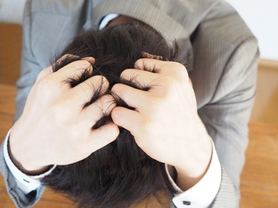 頭を抱え込み、悩む男性(イメージ)