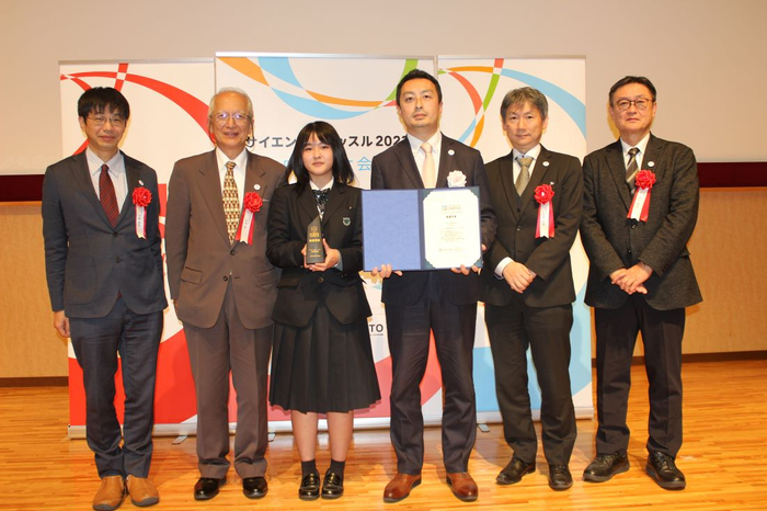 口頭発表で最優秀賞を受賞し、審査員とともに記念写真に納まる門田さん（左から３人目）