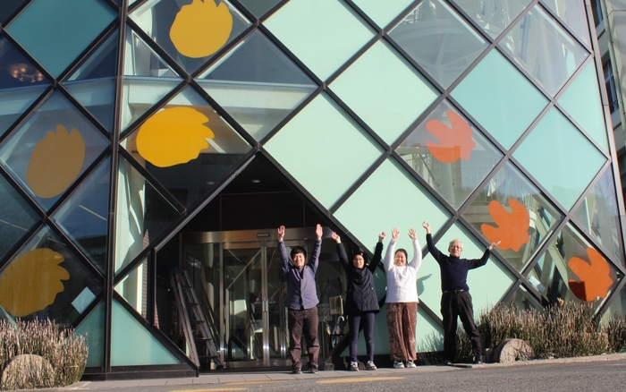 カッティングシートの取り付けが完了して喜ぶ学生たち。右端が石垣館長