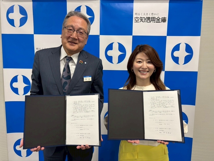 提携書を掲げる国井代表取締役(右)と熊尾理事長