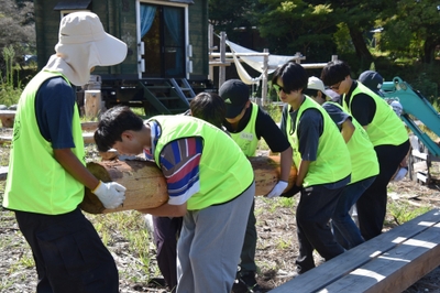 重い丸太を協力して運ぶ