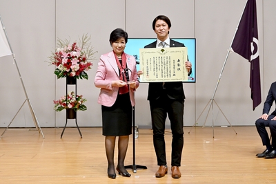 © 東京都 -モデル企業 表彰式の写真- (正面左:東京都知事 小池百合子氏、右:当社 執行役員 スポーツクラブ事業本部長 落合浩二)